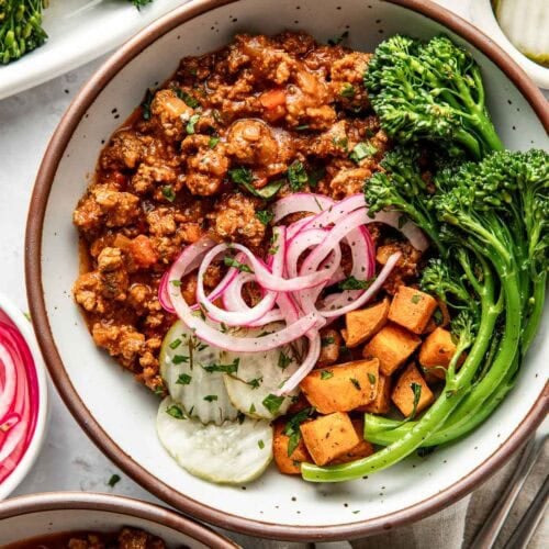 Overhead view bowl filled with serving of sloppy joe mixture with side of roasted sweet potato bites and roasted broccolini