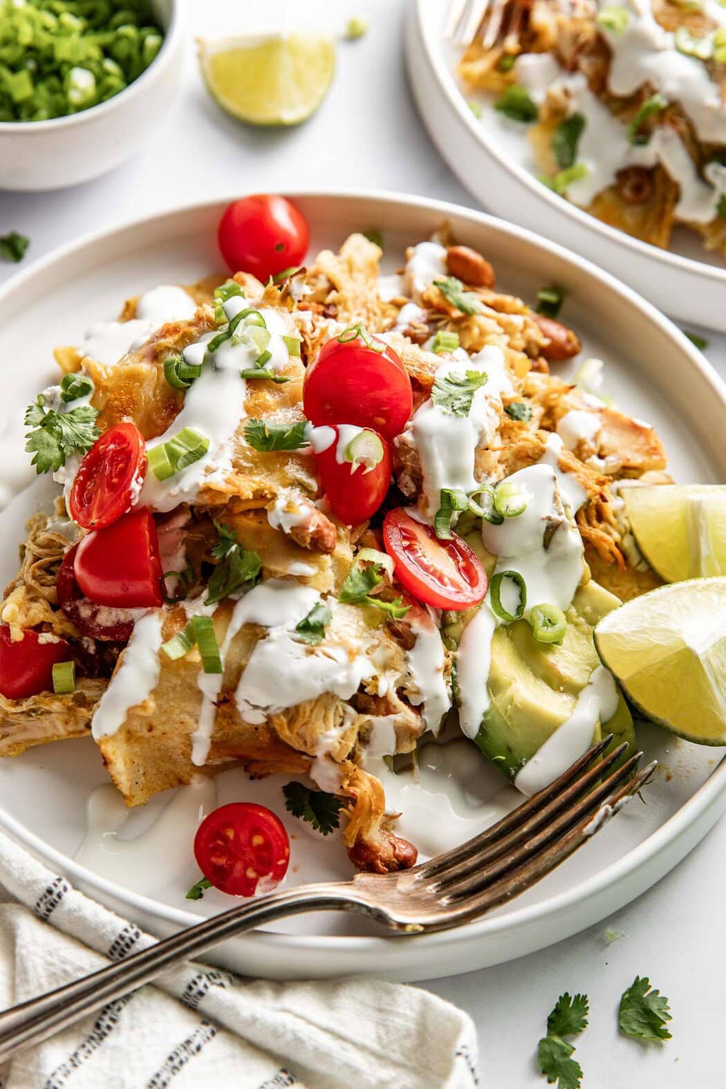 Close up view of a plate filled with Skillet Chicken Enchiladas topped with green onions and sour cream