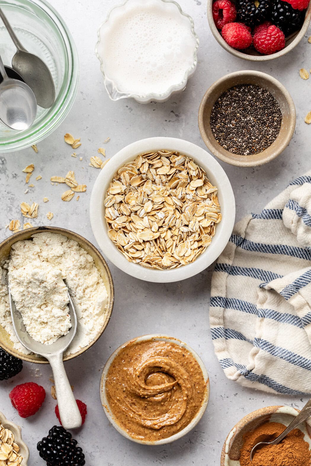 Overhead view of a variety of ingredients for Protein Overnight Oats in different sized bowls.