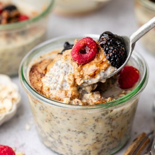 Close up view of a glass jar filled with Protein Overnight Oats topped with fresh colorful berries.
