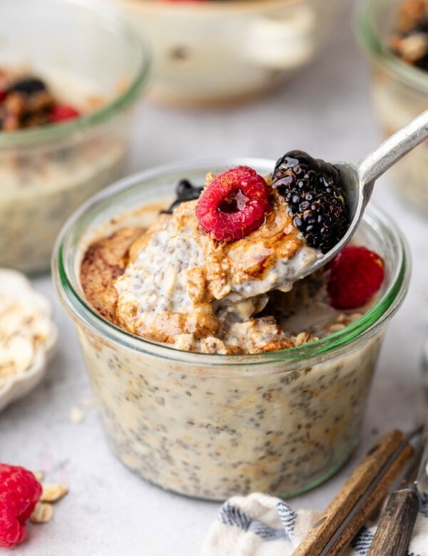 Close up view of a glass jar filled with Protein Overnight Oats topped with fresh colorful berries.