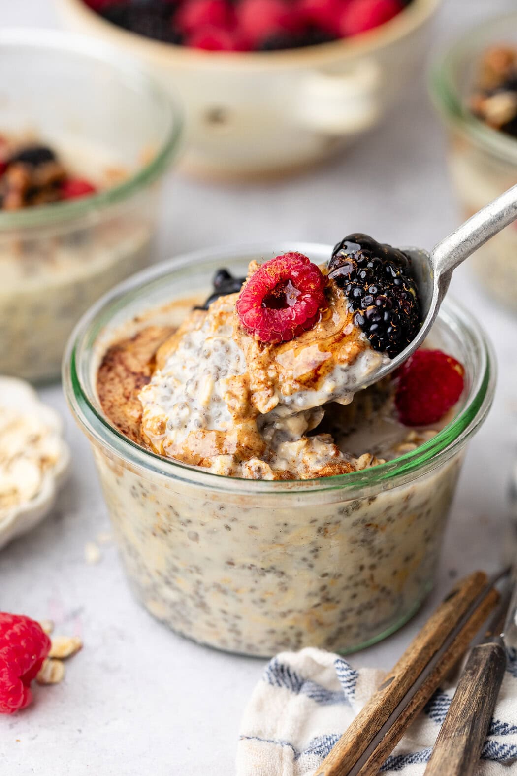 Close up view of a glass jar filled with Protein Overnight Oats topped with fresh berries and honey.
