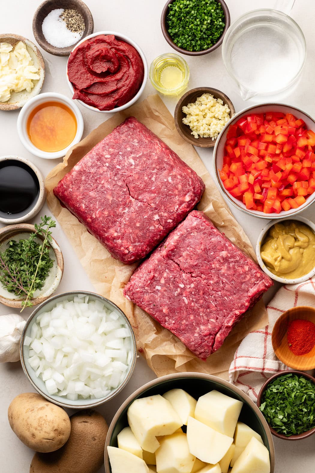 Overhead view of a variety of ingredients for Sloppy Joe Casserole in different sized bowls. 