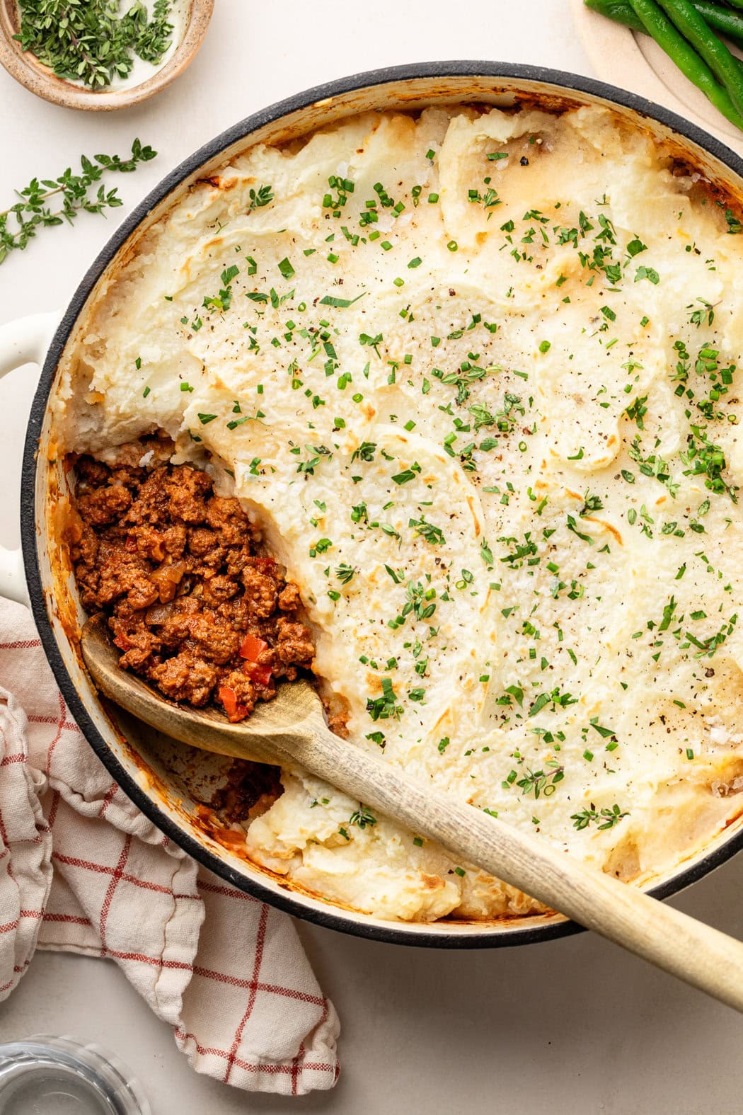 Close up view of a skillet of freshly baked Sloppy Joe Casserole with a wooden spoon scooped into the side. 