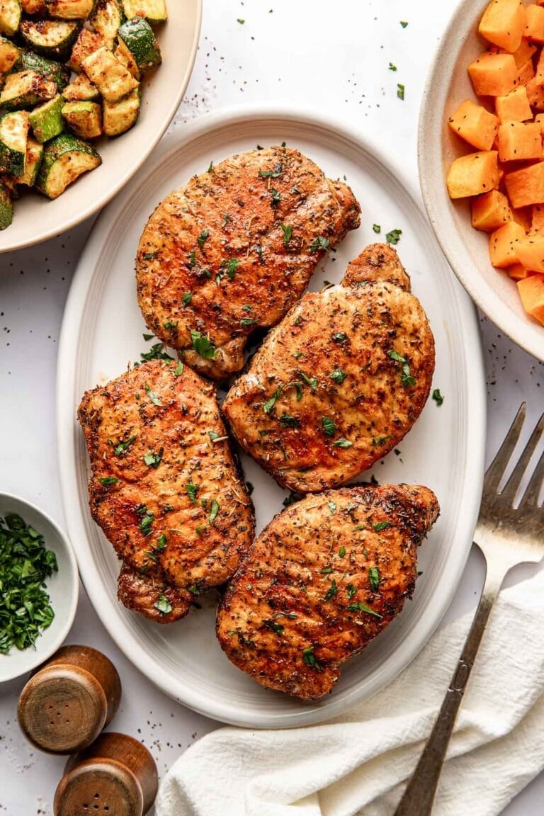Overhead view of a platter filled with freshly roasted porkchops showing crisp outside and perfectly seasoned.