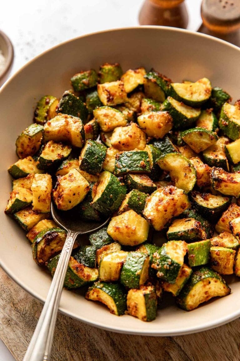 Close up view of a crispy air fryer zucchini bites in a bowl with a spoon on the side.