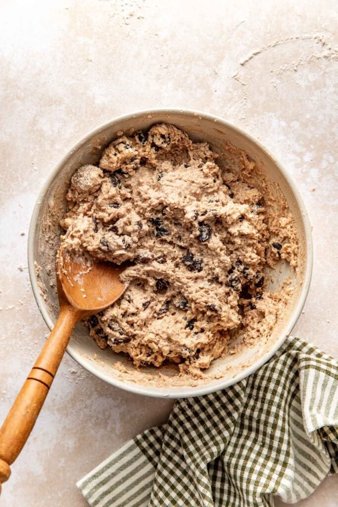 Bowl of soft craggy biscuit dough studded with raisins.