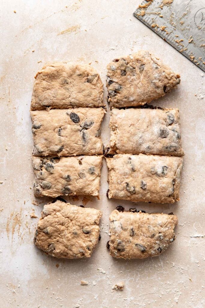 Eight pieces of cinnamon raisin biscuit dough that have been cut using a bench scraper.