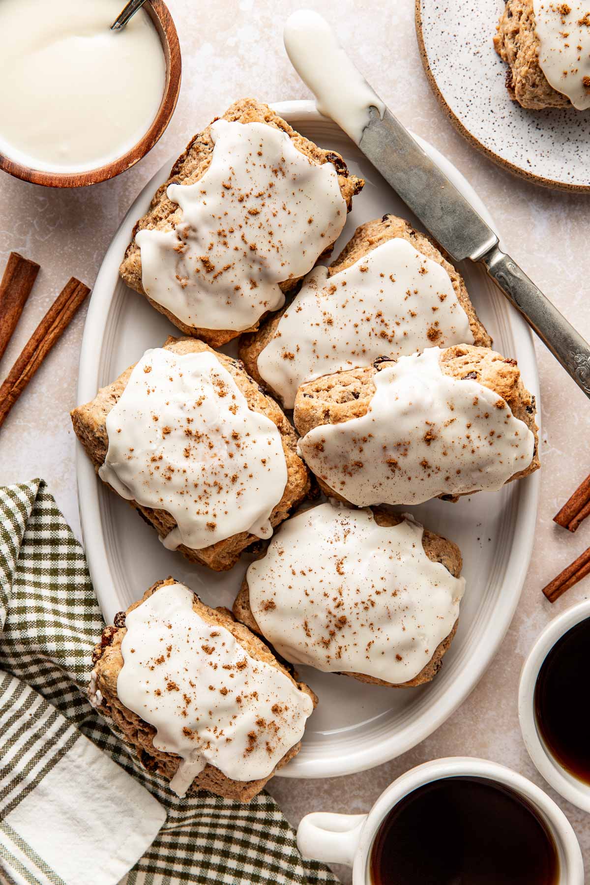 Overhead view of a white oblong platter filled with Cinnamon Raisin Biscuits topped with icing and sprinkled with cinnamon. 