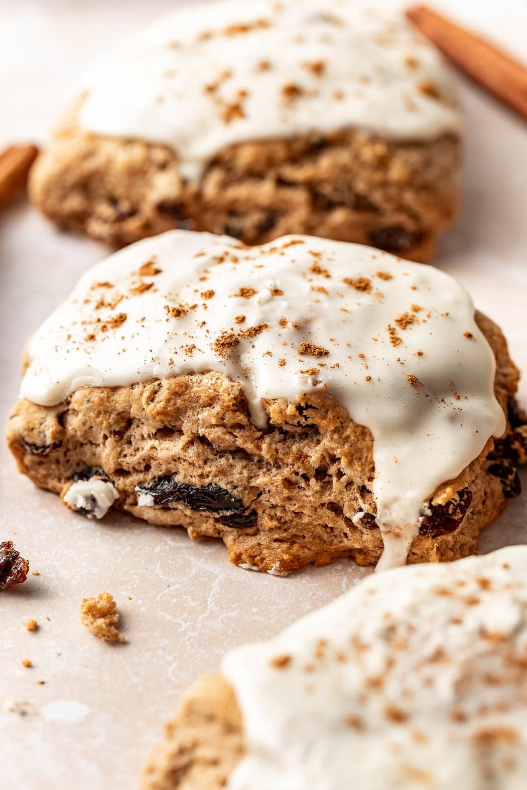 Close up view of a Cinnamon Raisin Biscuit topped with icing and sprinkled with cinnamon.