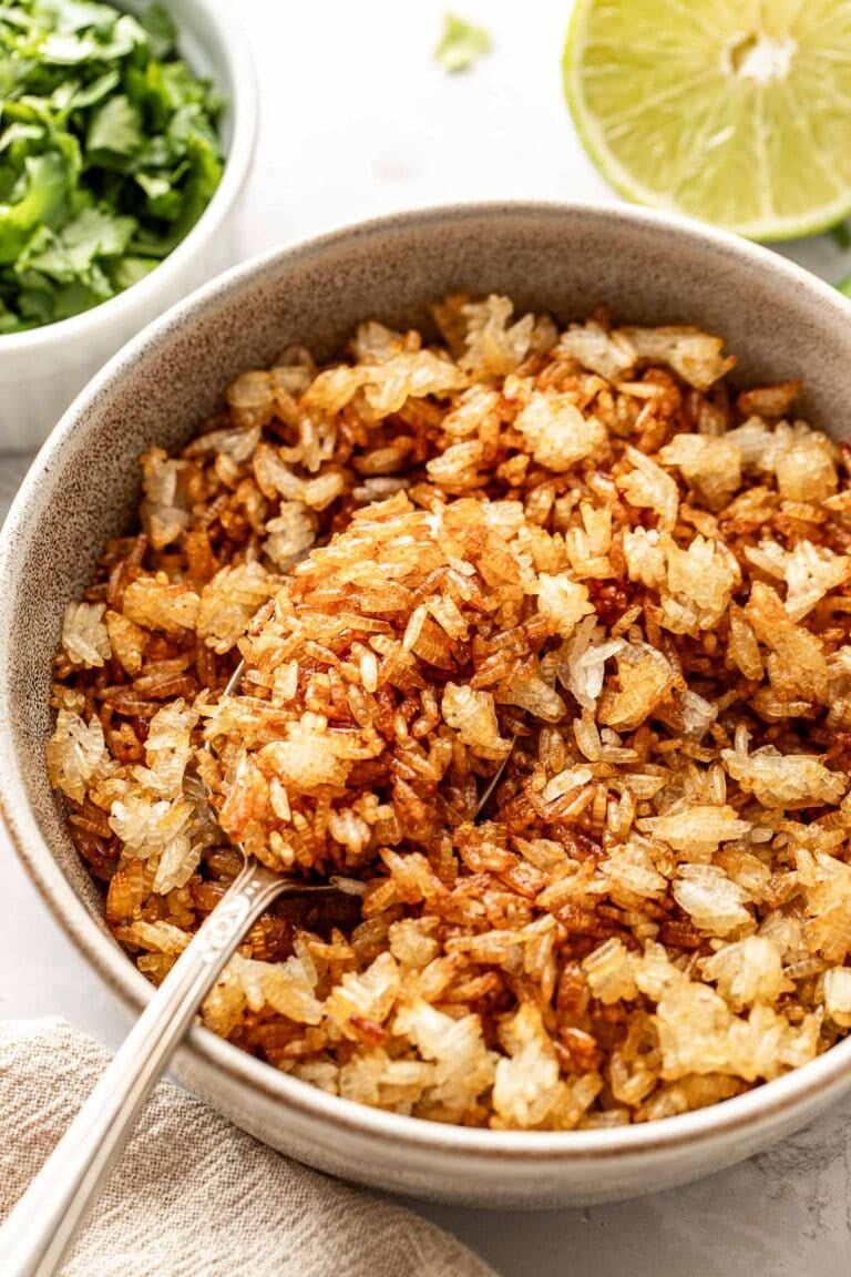 Close up view of a bowl filled with crispy roasted rice with a spoon in the bowl.