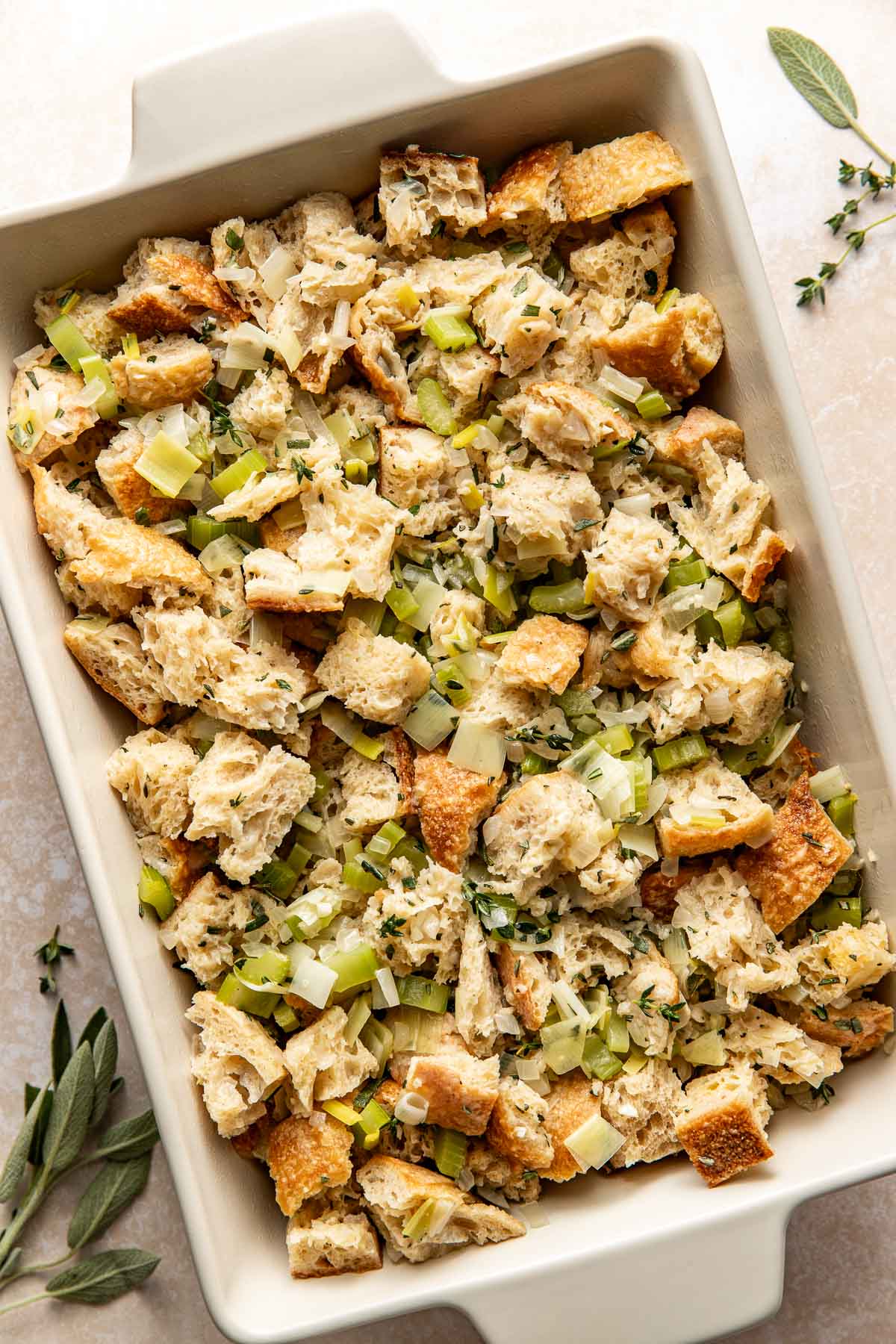 Overhead view of a white baking dish filled with stuffing mixture ready for baking.
