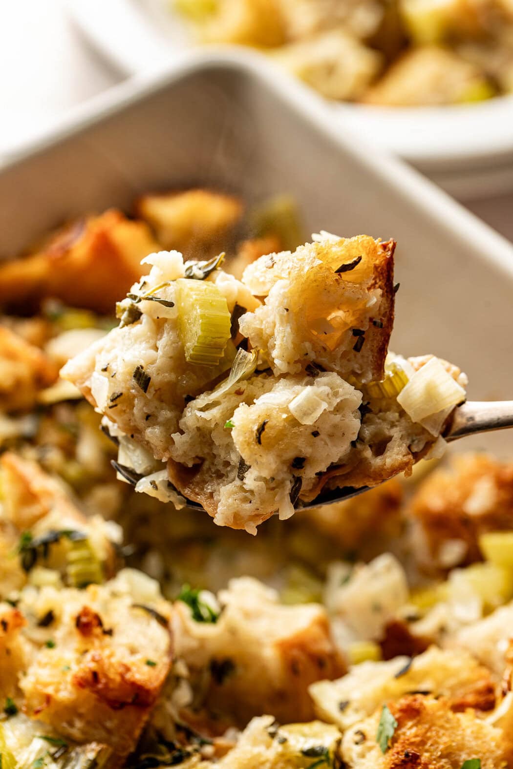 Close up view a spoonful of freshly baked stuffing showing the herbs and texture.