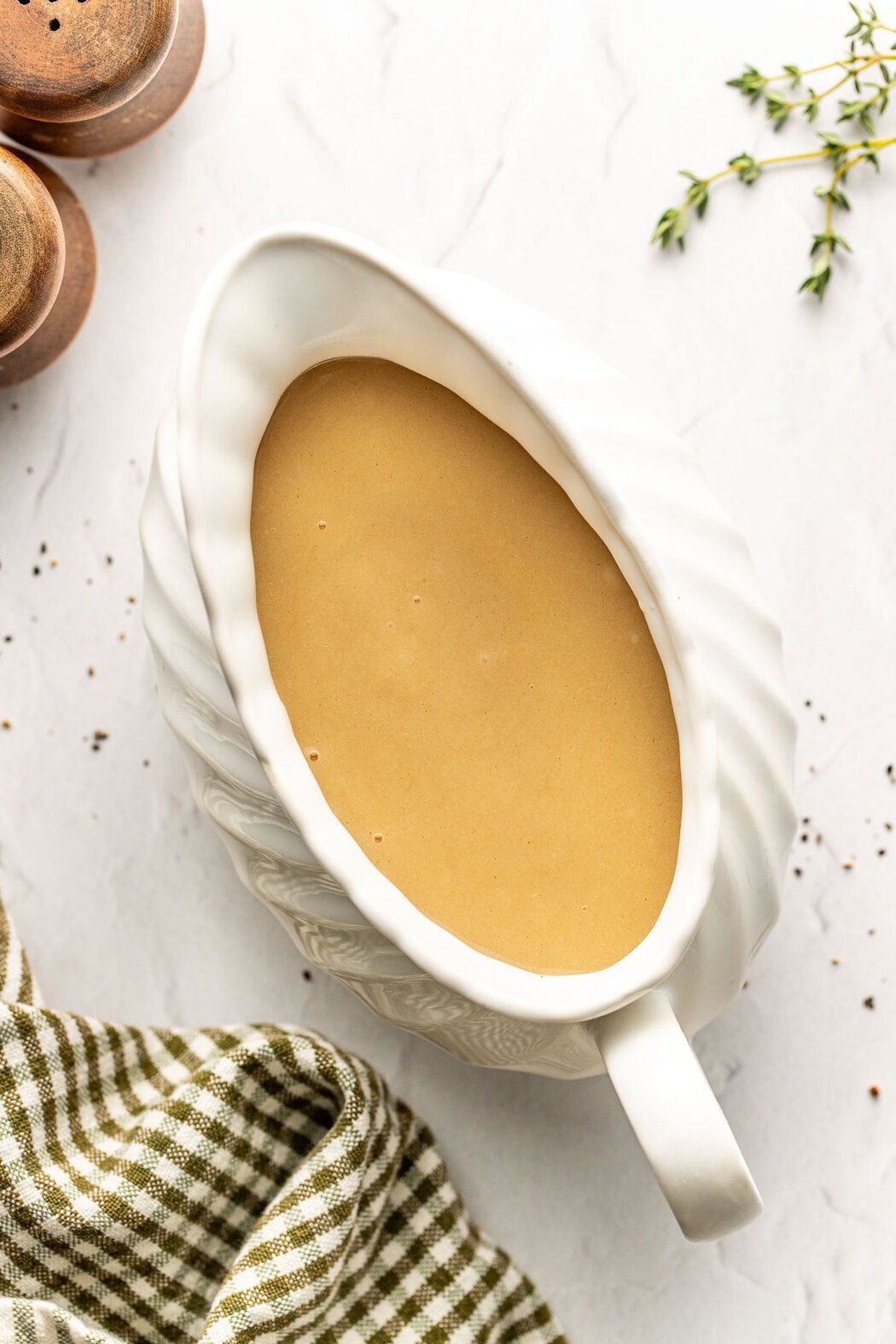Overhead view of a white gravy boat filled with Turkey Gravy on a marble countertop. 