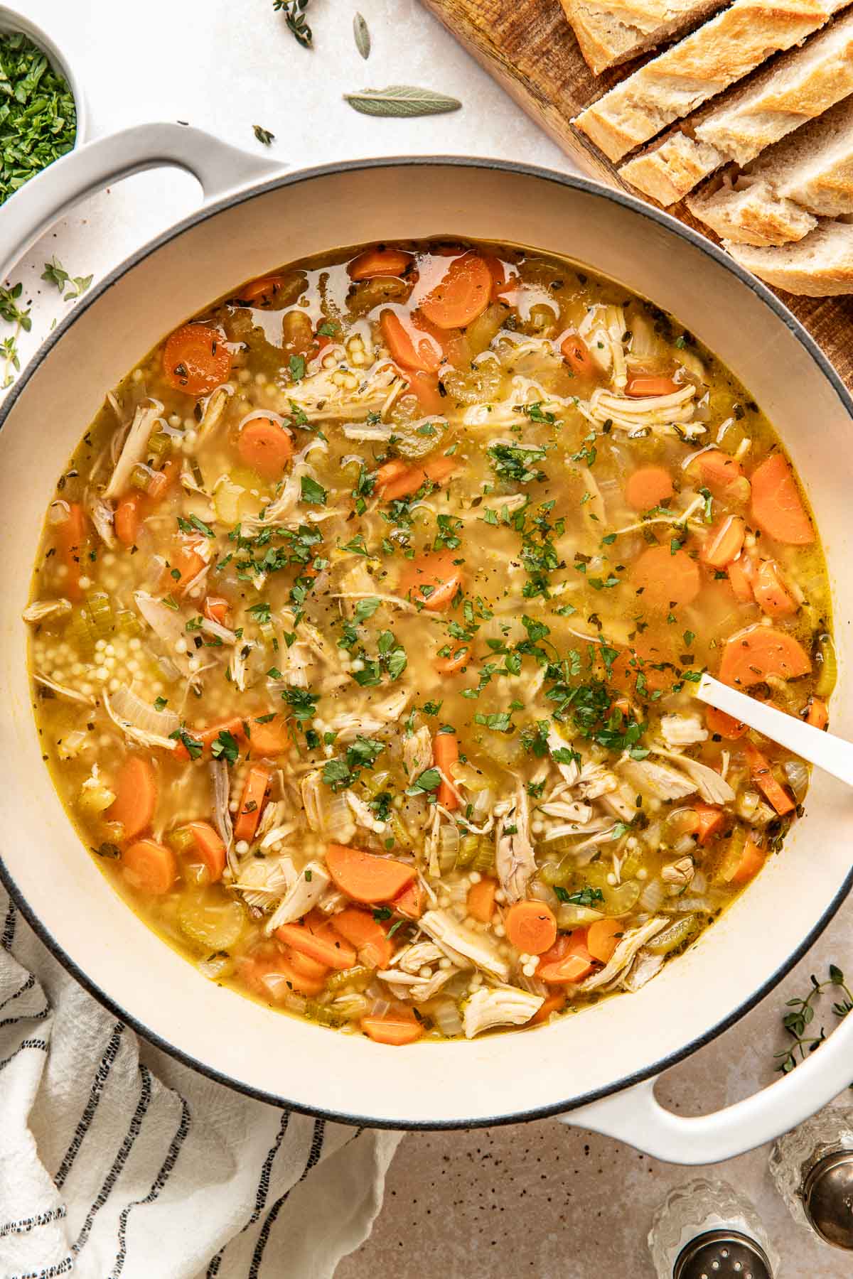 Overhead view of a Dutch oven filled with Turkey Soup topped with fresh herbs and black pepper. 