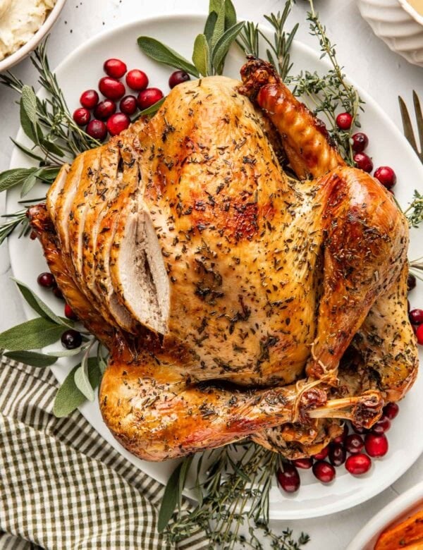 A whole roasted turkey on a platter with side dishes around it