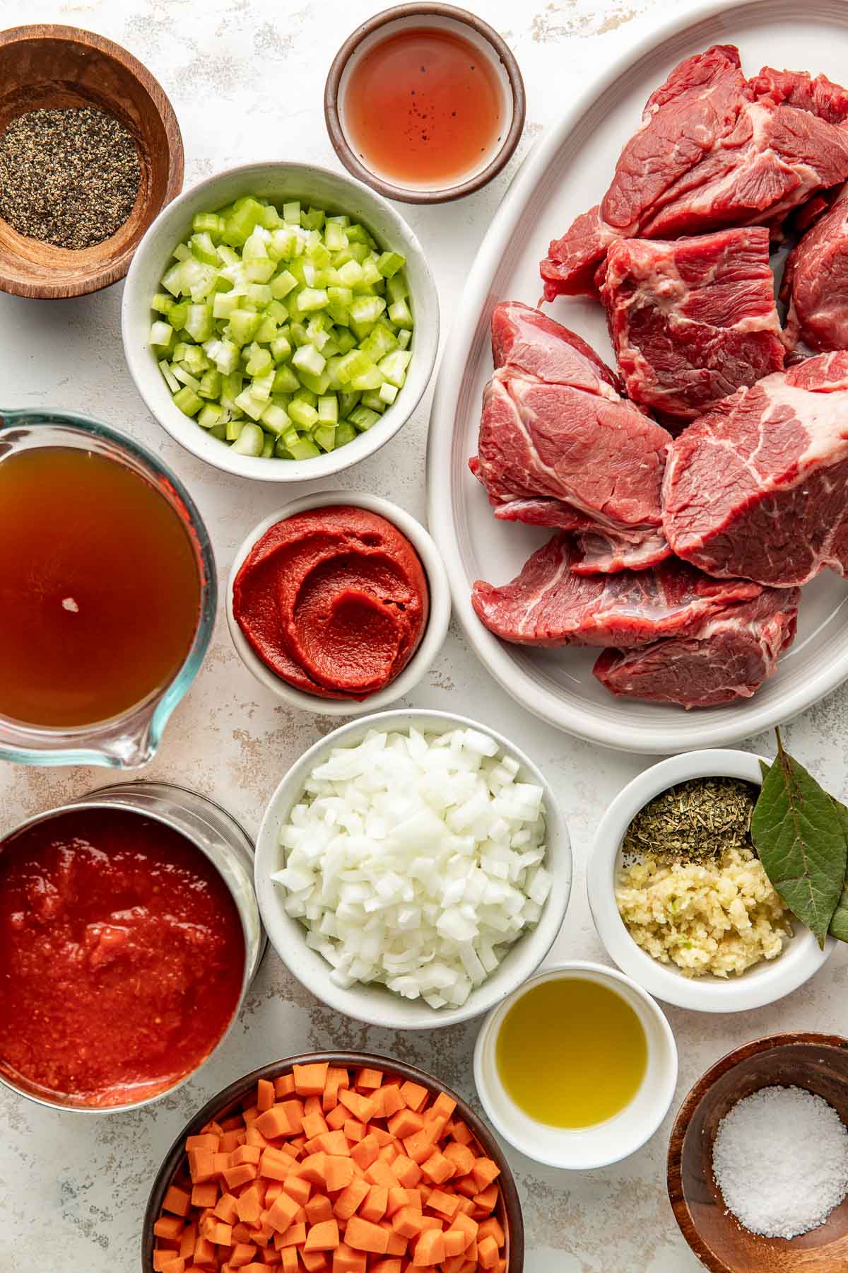 Overhead view of a variety of ingredients for Oven-Braised Beef Ragu in different sized bowls.