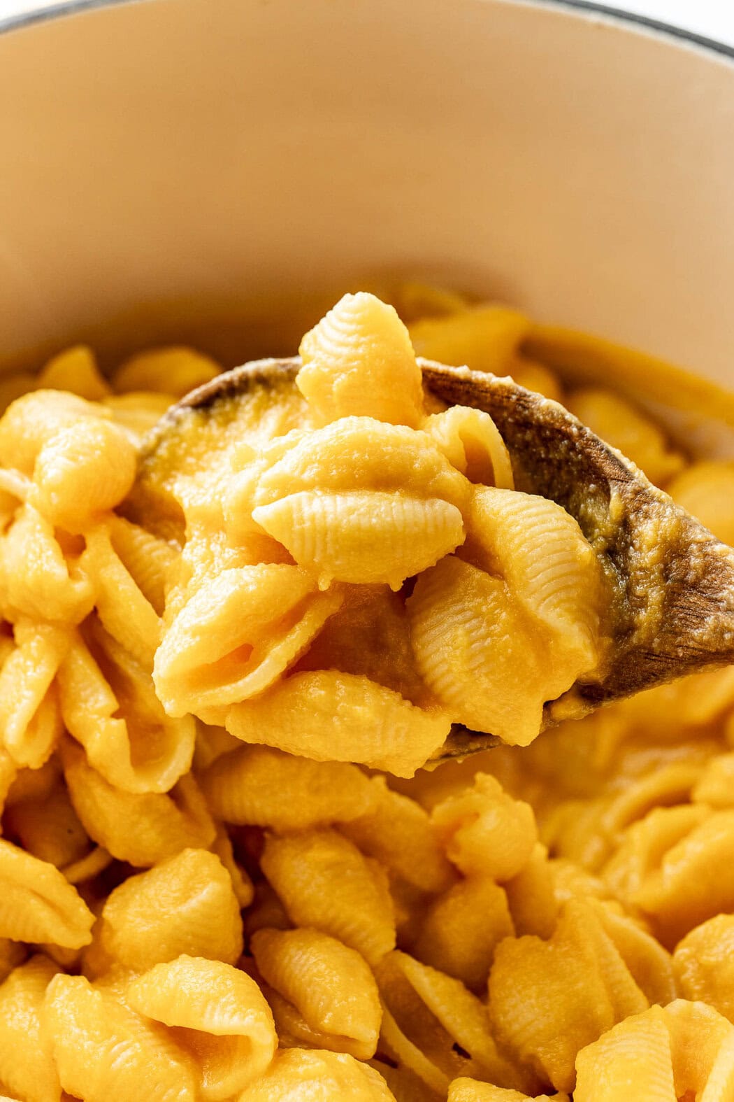 Close up view of a wooden spoon scooping a section of Butternut Squash Mac and Cheese.