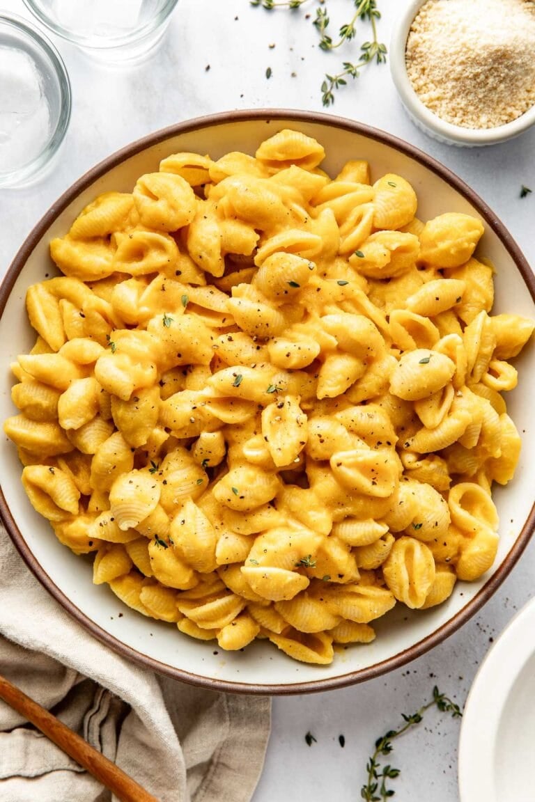 Overhead view of a ceramic bowl filled with Butternut Squash Mac and Cheese topped with black pepper.