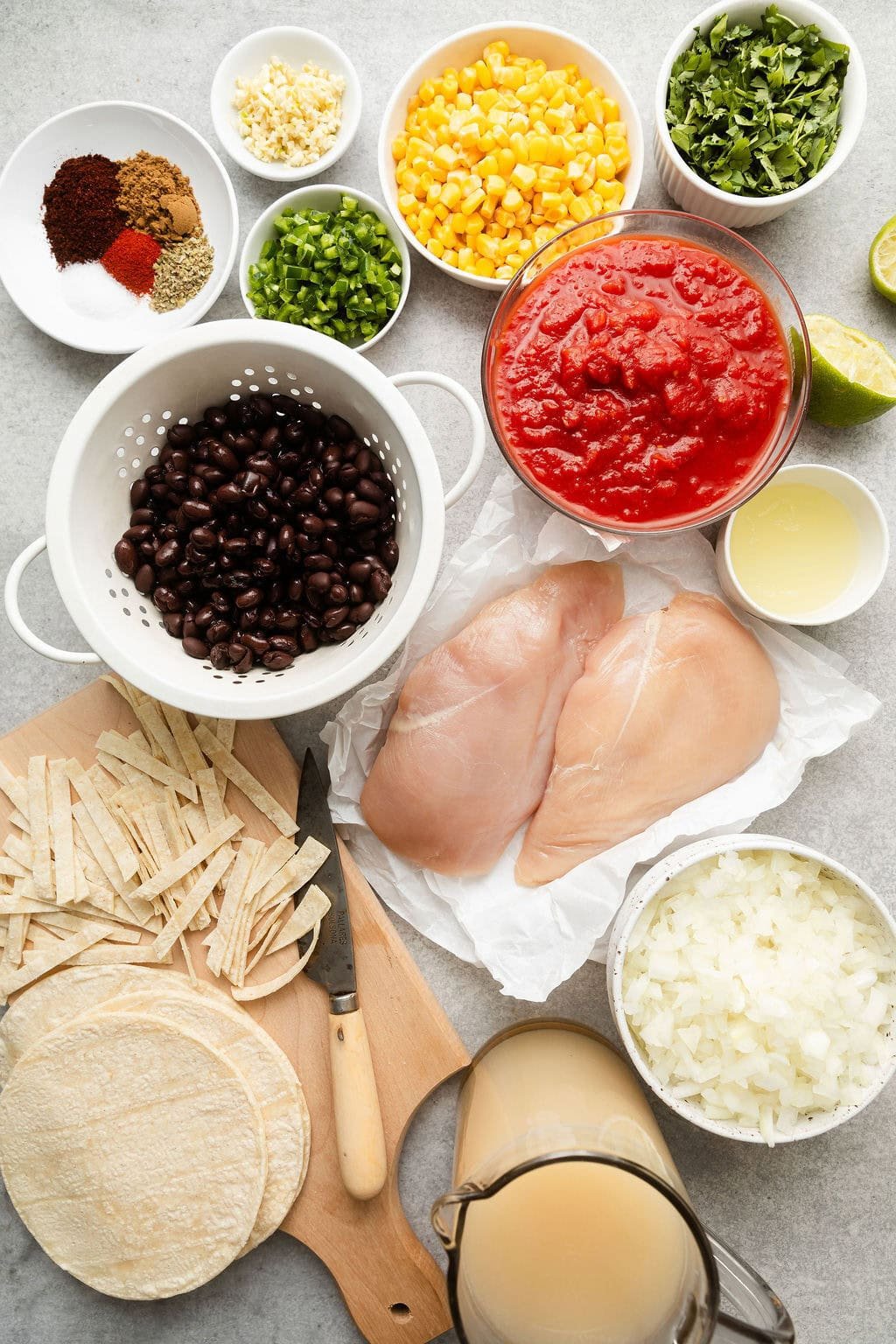 Overhead view of a variety of ingredients for Chicken Tortilla Soup in different sized bowls.