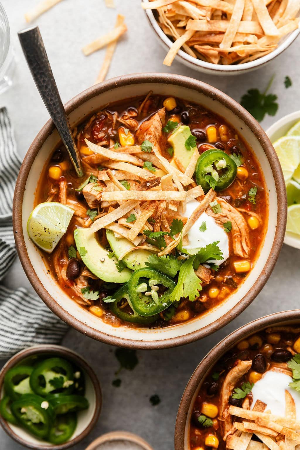 Overhead view of a bowl filled with Chicken Tortilla Soup topped with sliced jalapenos, avocado, and fresh cilantro.