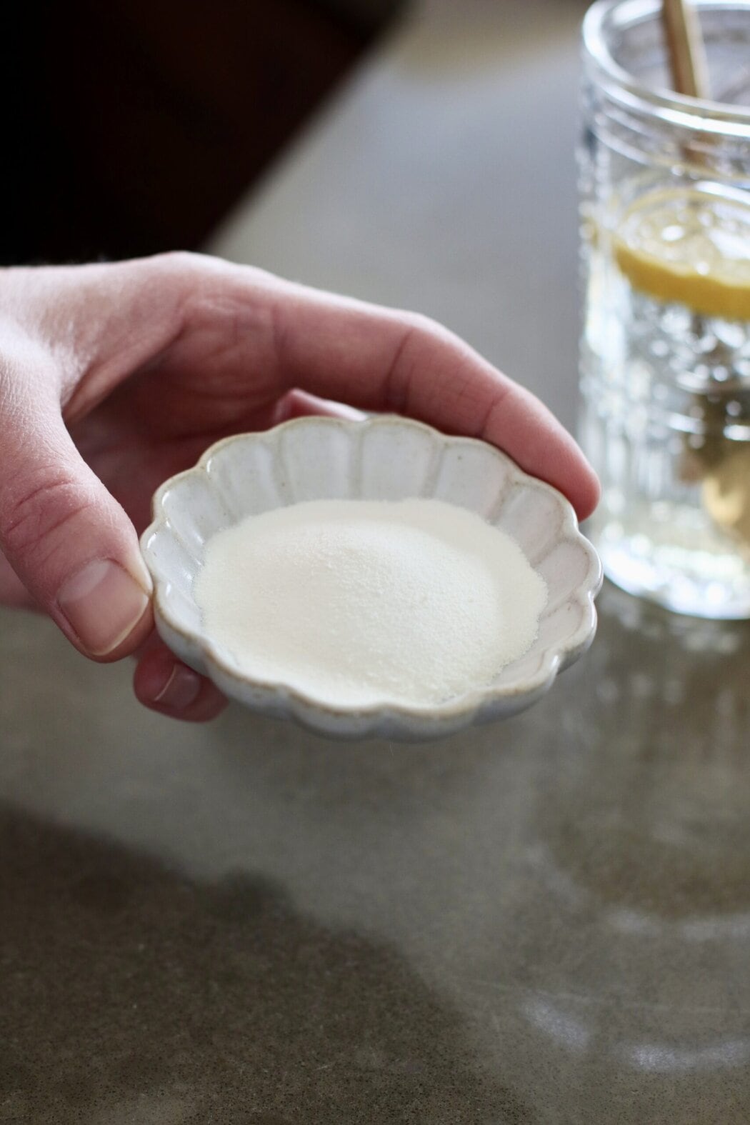 Close up view of a dish of collagen being held by a woman's hand.