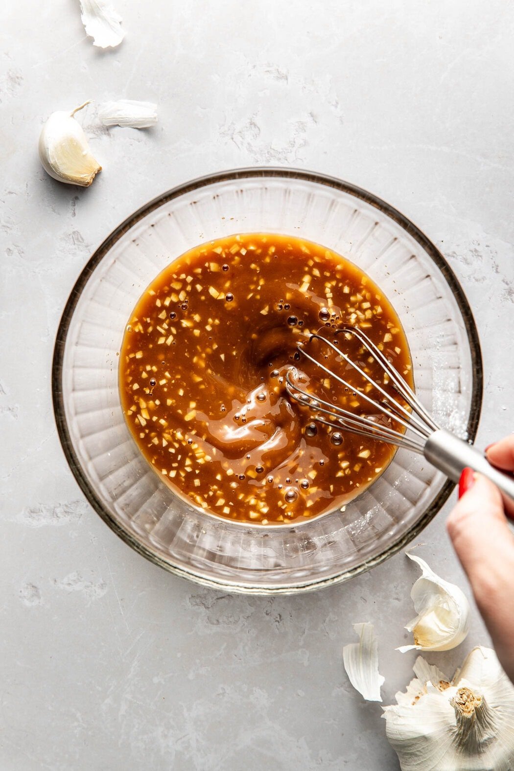 Overhead view of a glass bowl filled with Stir Fry Sauce being mixed with a stainless-steel whisk.