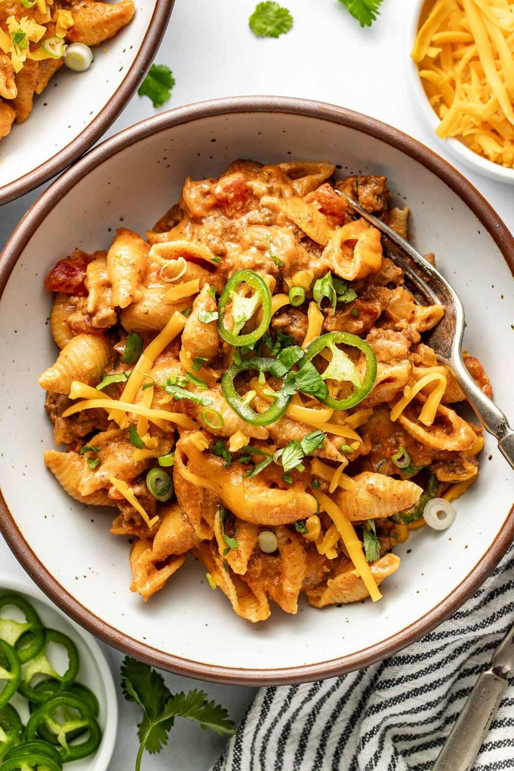 Overhead view of a plate of Taco Pasta topped with melted cheese and sliced jalapenos.