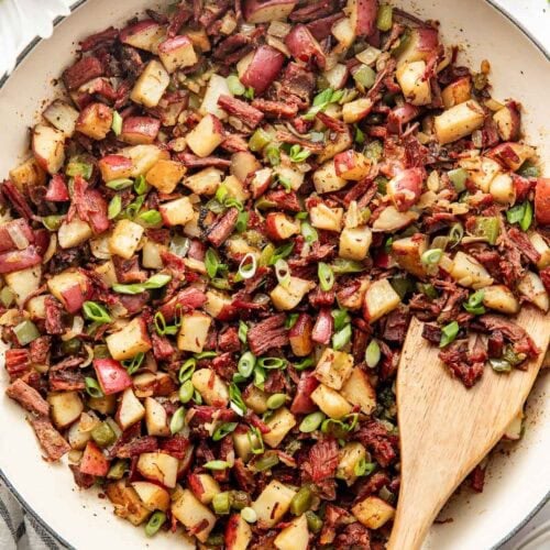 Overhead view of a skillet of Corned Beef Hash topped with fresh herbs.