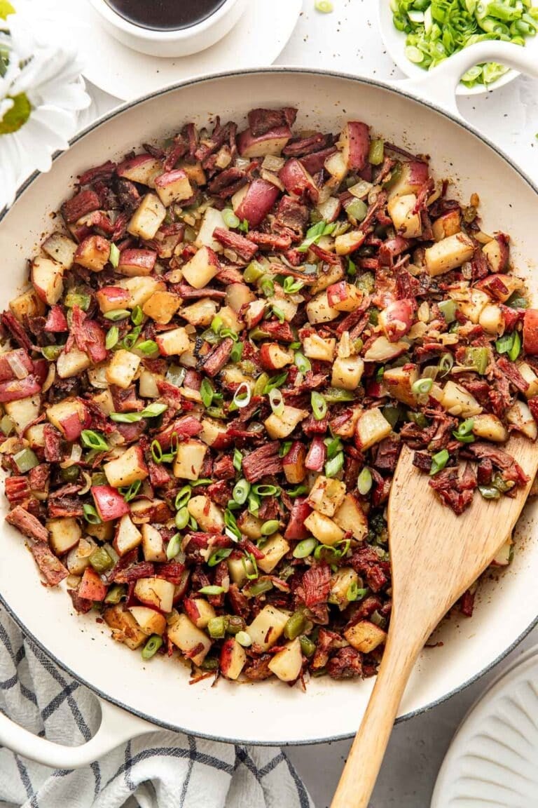 Overhead view of a skillet of Corned Beef Hash topped with fresh herbs.