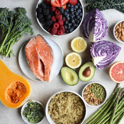 Overhead view of a variety of fruits, vegetables, and salmon on a marble countertop.