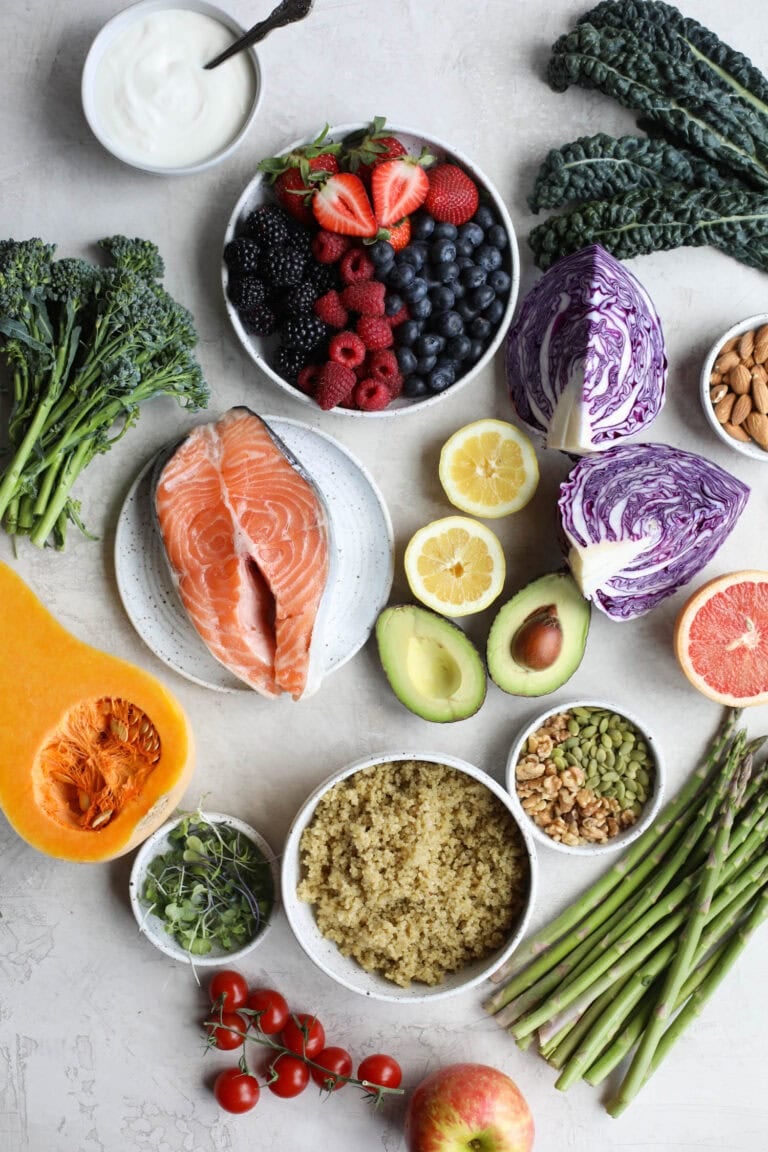Overhead view of a variety of fruits, vegetables, and salmon on a marble countertop.