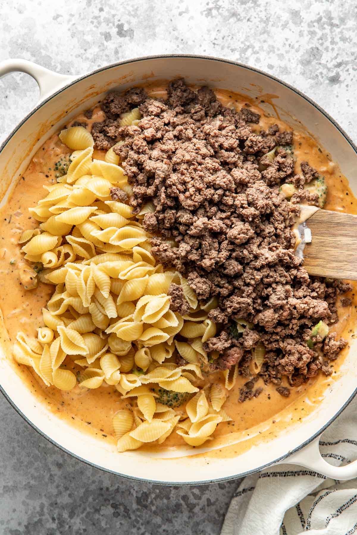 Overhead view of a skillet filled with ground beef and shell noodles in a creamy cheese sauce.