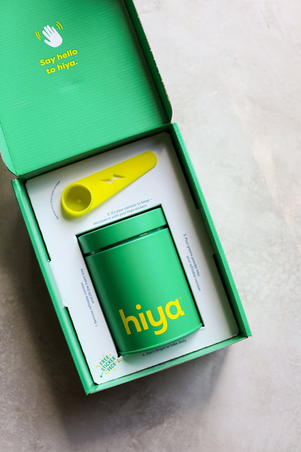 Overhead view of a box of hiya drink mix with a canister and scoop inside the box to show packaging.