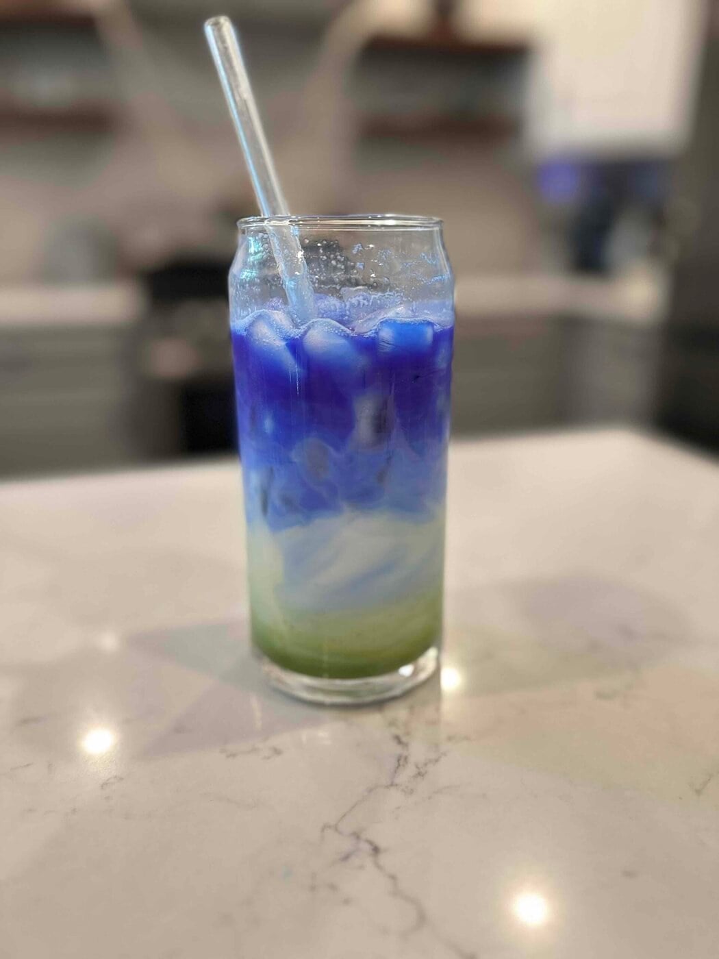 Close up view of a layered matcha iced drink with a straw in the glass.