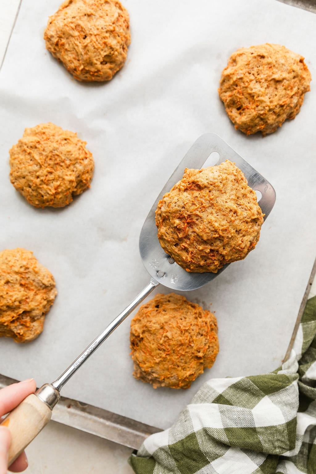 Overhead view of a parchment lined sheet pan filled with freshly baked carrot cake cookies. 
