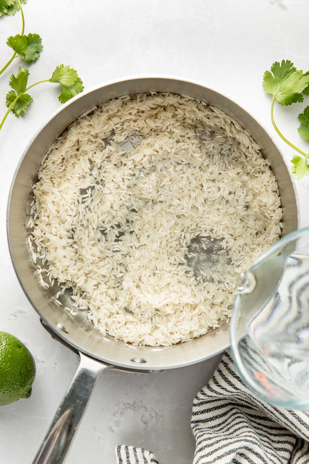 Overhead view of a pot of rice with water being poured on top.