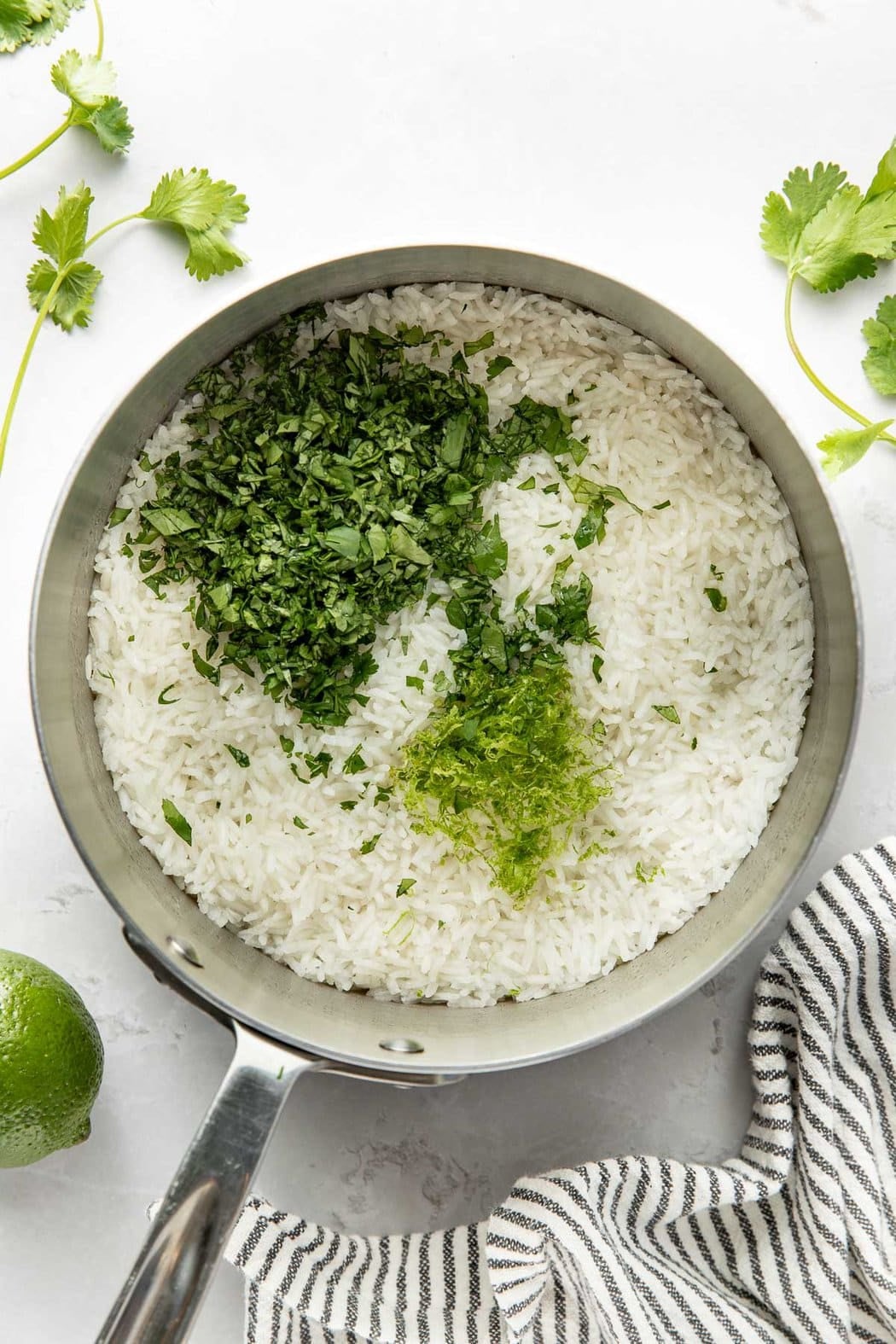 Overhead view of a pot filled with cooked rice topped with fresh cilantro and lime zest.