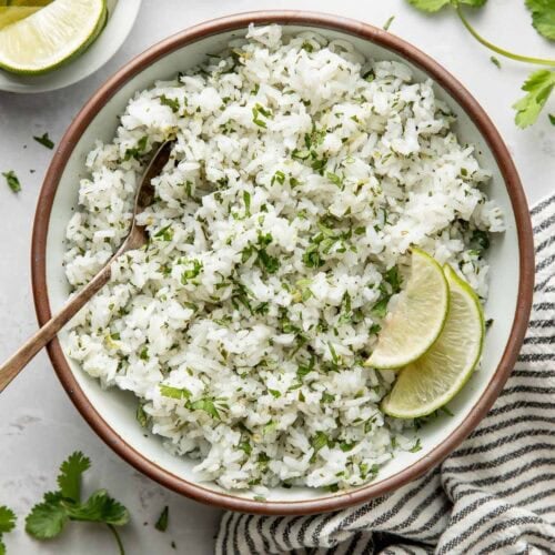 Overhead view of a bowl of Cilantro Lime Rice garnished with lime wedges.
