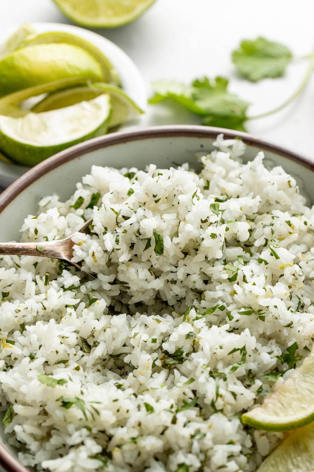 Close up view of a bowl of Cilantro Lime Rice with a wooden spoon stuck into the rice.