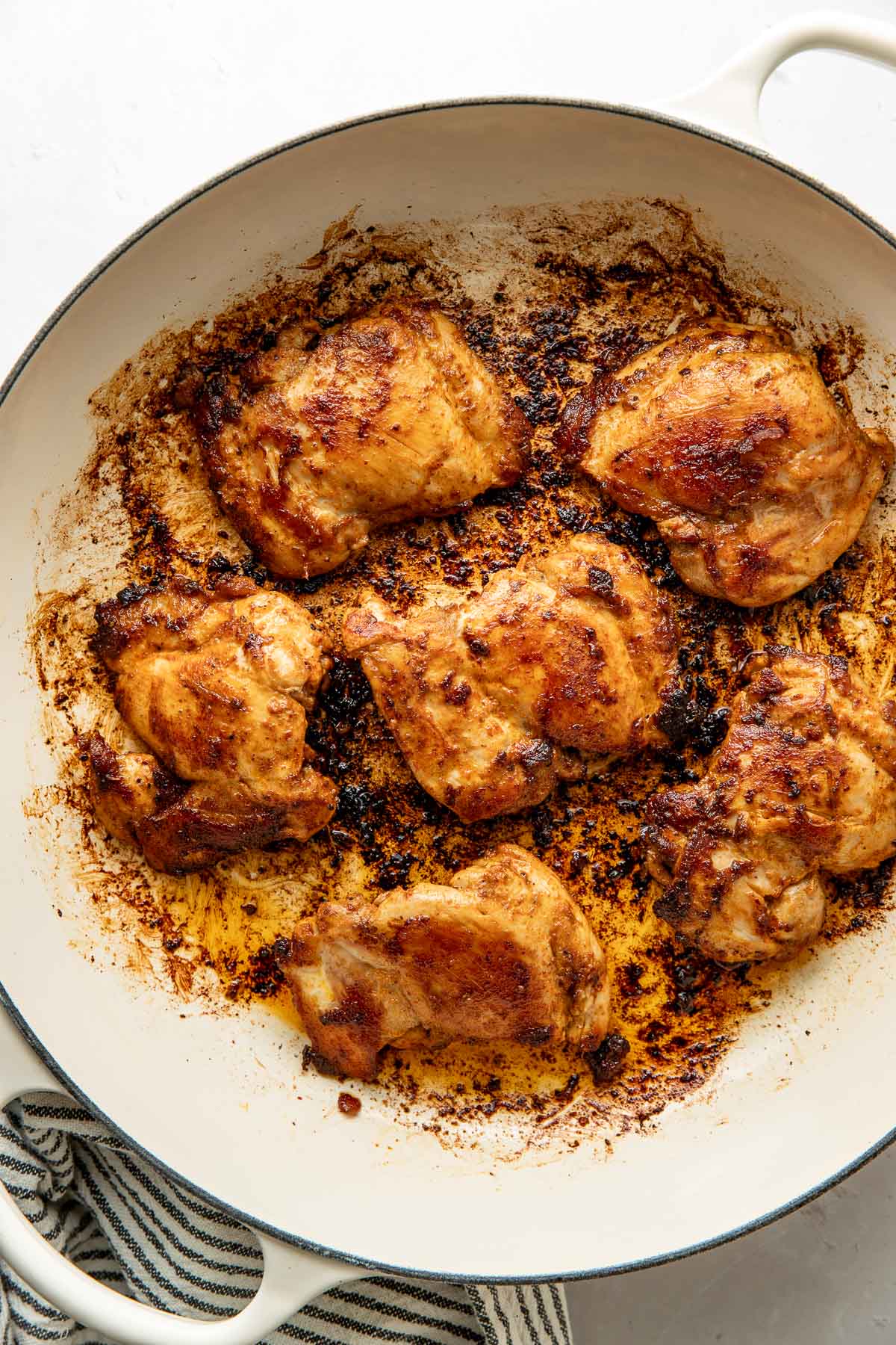 Overhead view of a skillet filled with cooked chicken thighs.