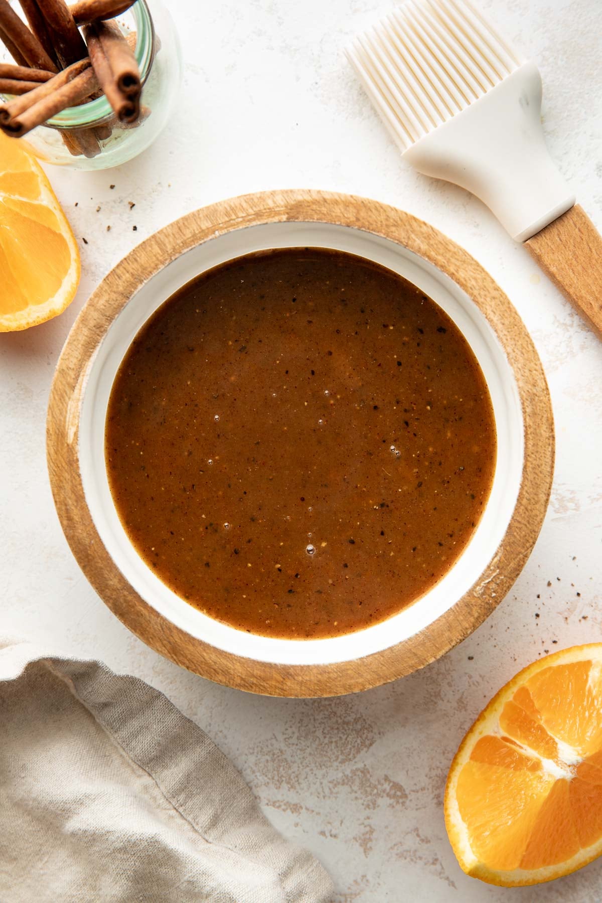 Overhead view of a small saucepan filled with ham glaze next to sliced oranges.