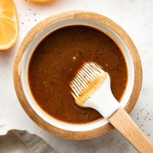 Overhead view of a small bowl filled with Ham Glaze with sliced oranges on the side of the dish.