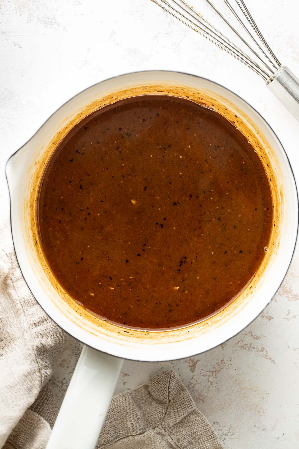 Overhead view of a saucepan filled with a thickened ham glaze.