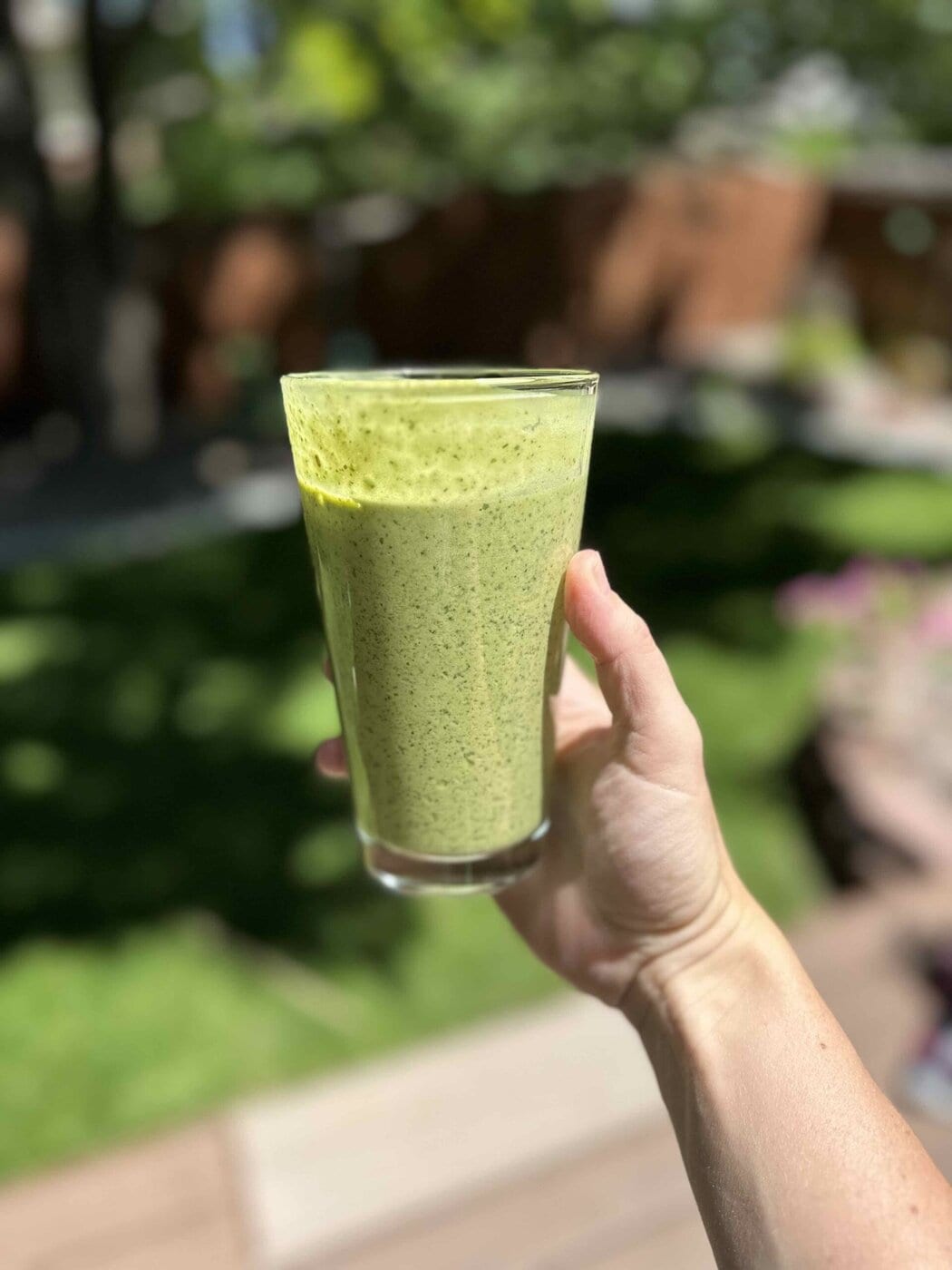 A hand holding a vibrant green matcha smoothie.