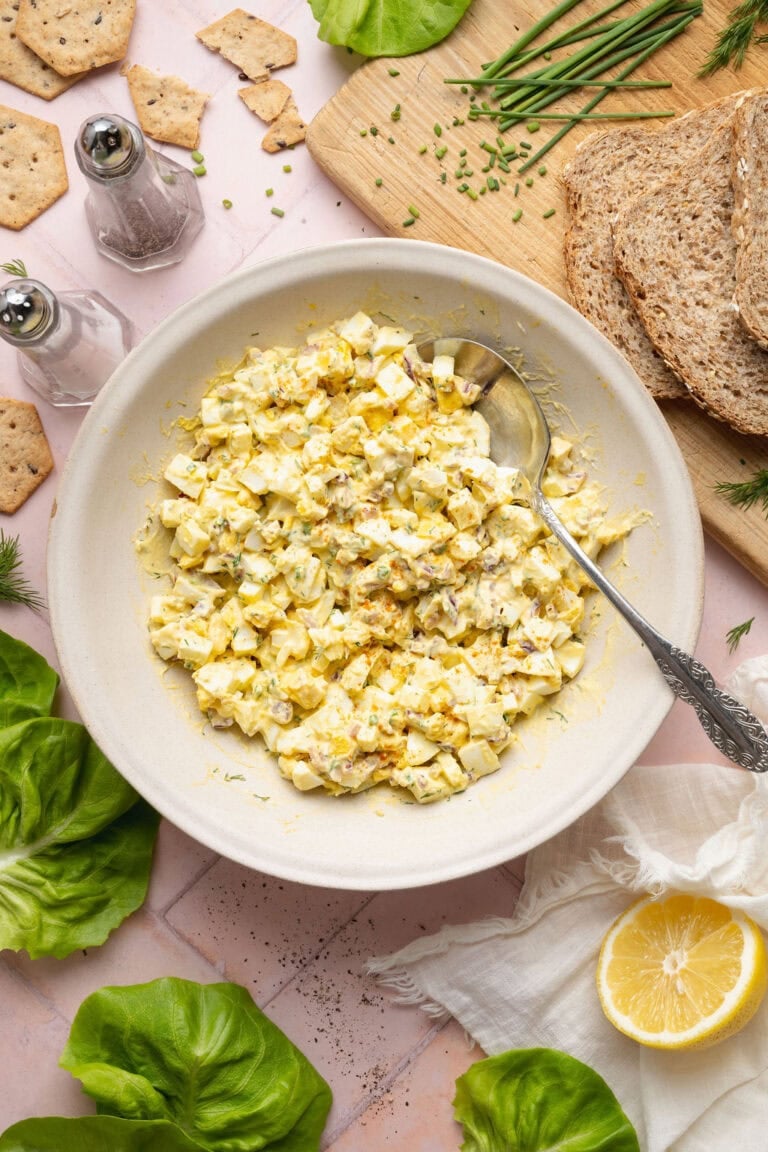 Overhead view of a bowl of egg salad topped with fresh chives and dill.