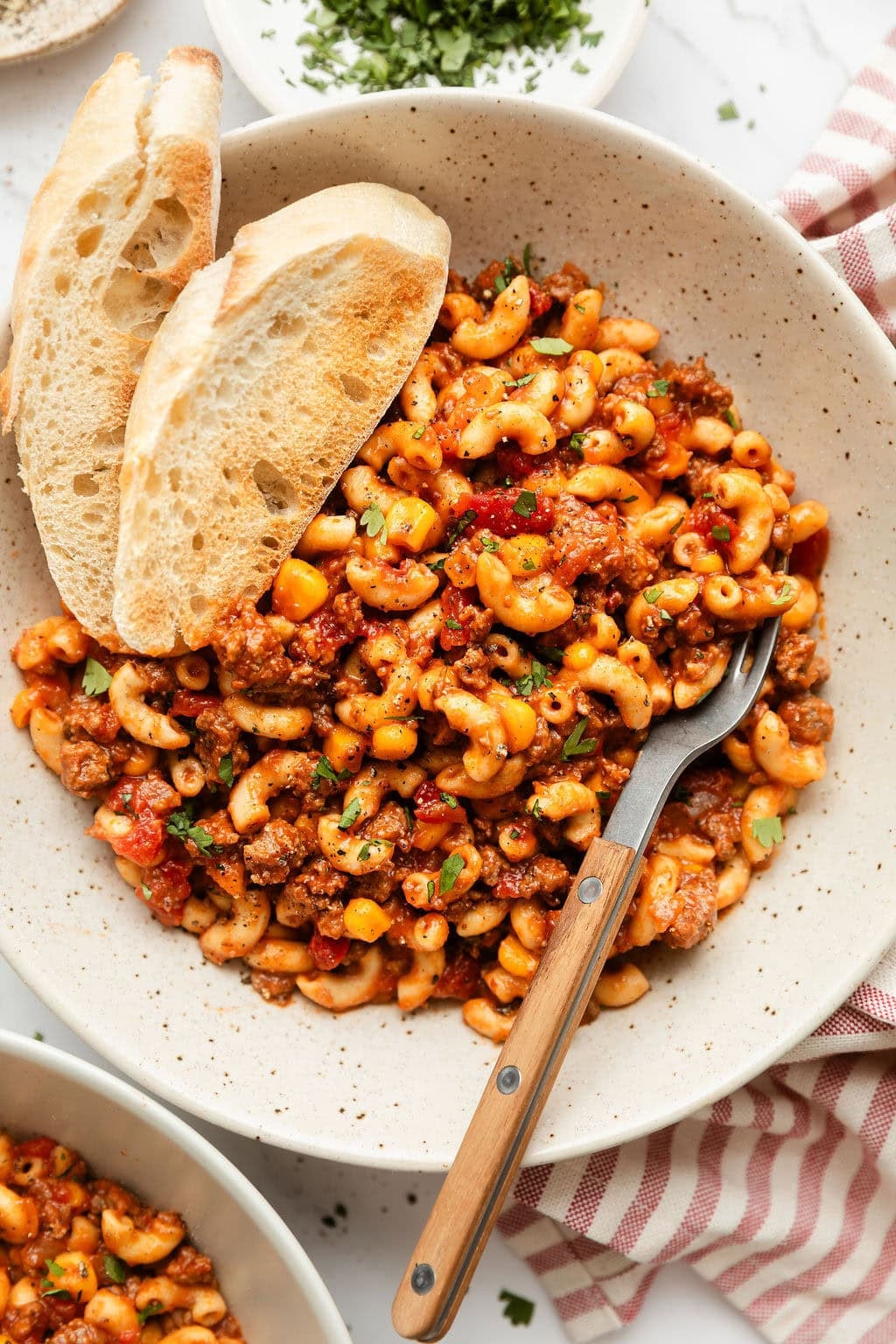 Overhead view of a plate of goulash with two pieces of bread stuck into the side.