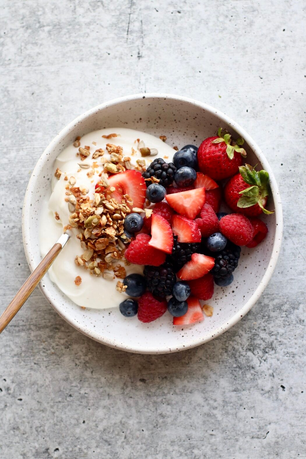 Overhead view of a small dish of yogurts and fresh berries.