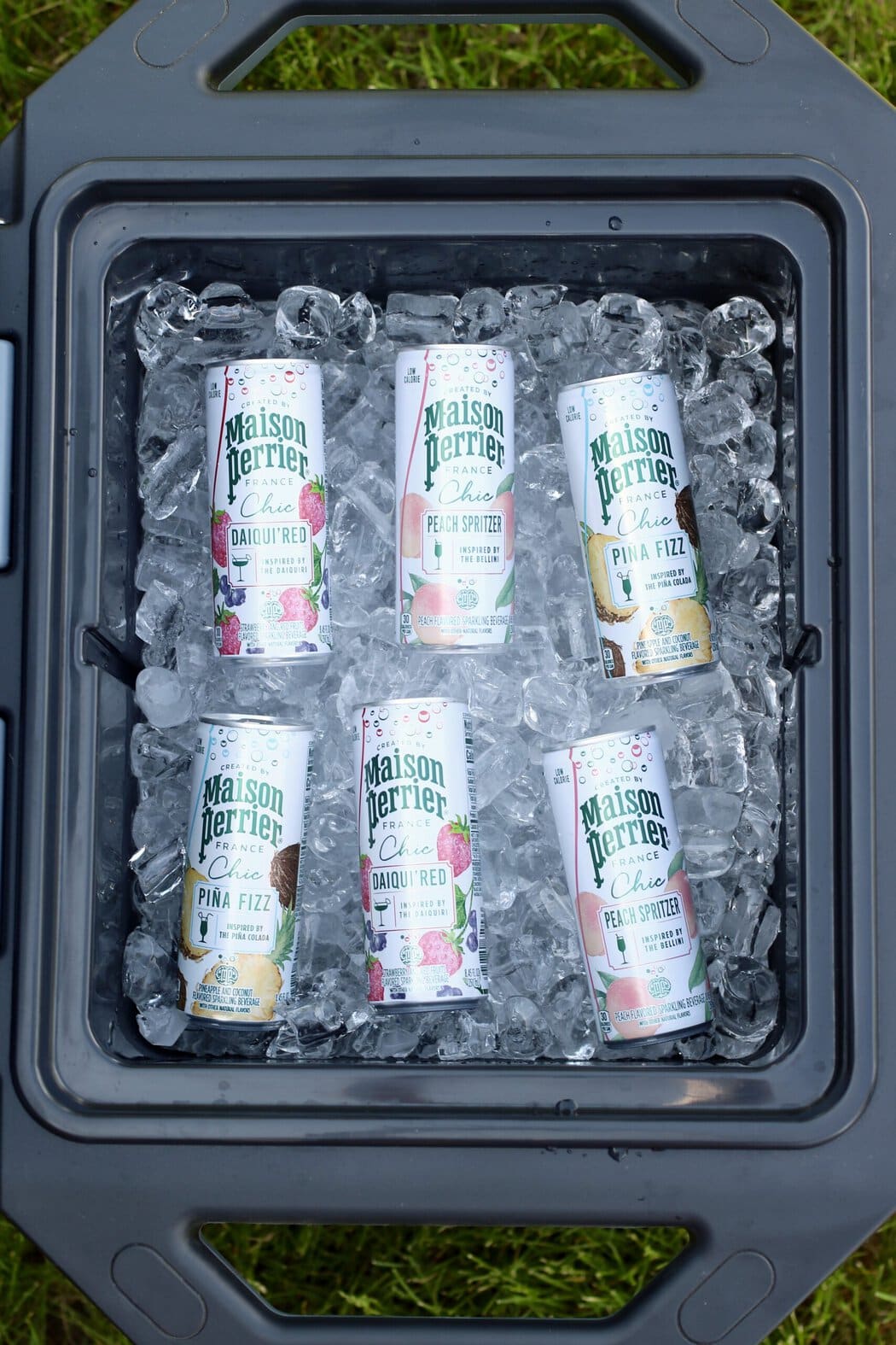 Overhead view of an open cooler filled with ice and canned mocktails of several different flavor choices including pina fizz.