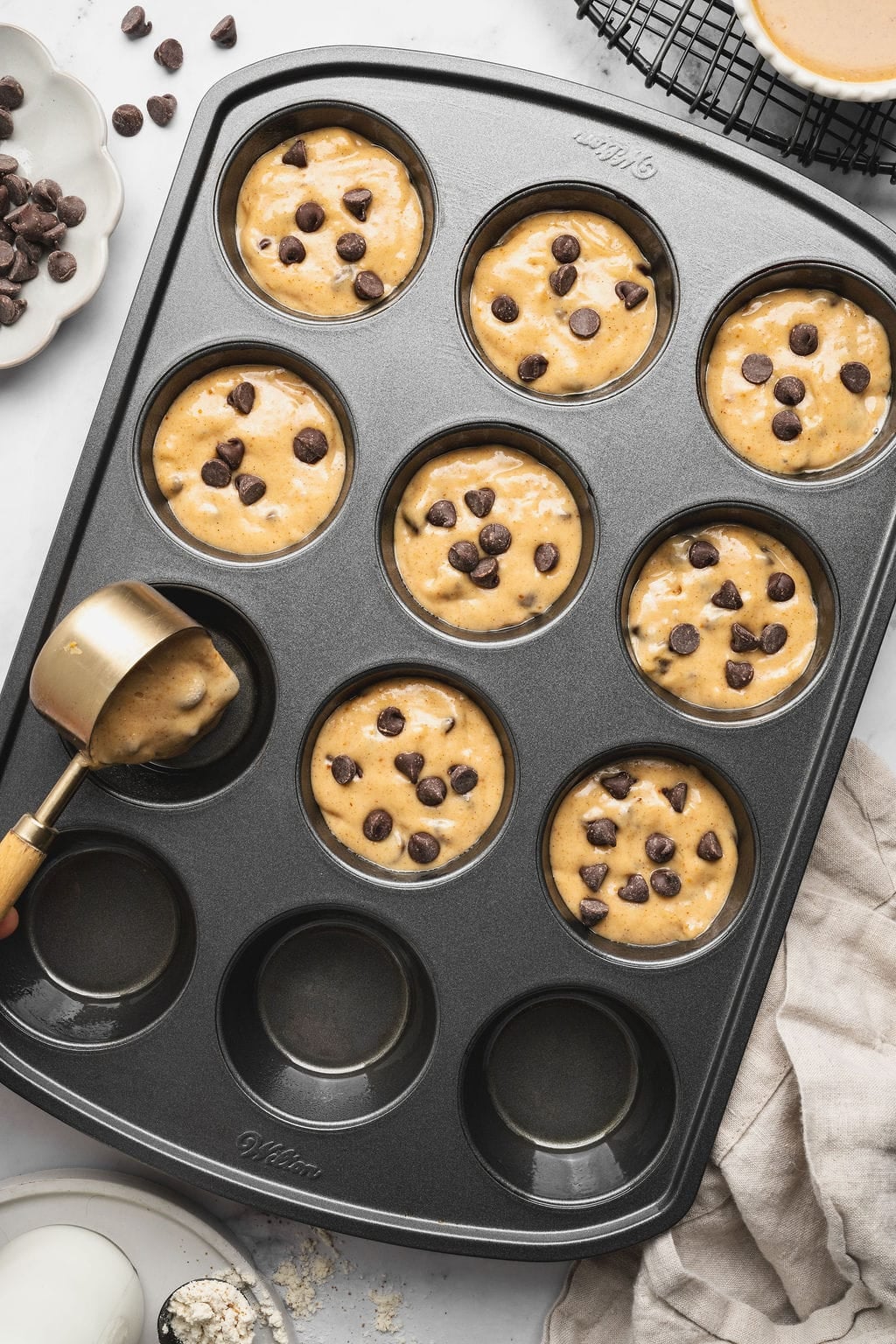 Overhead view of Peanut Butter Protein Muffin batter going into the wells of a muffin pan.